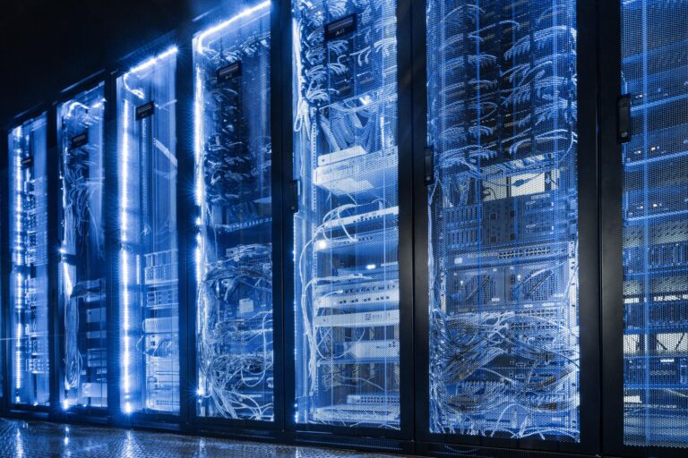 Ilustrasi data center cloud computing modern dengan server futuristik, chip AI pada motherboard, dan workstation teknologi berwarna biru.